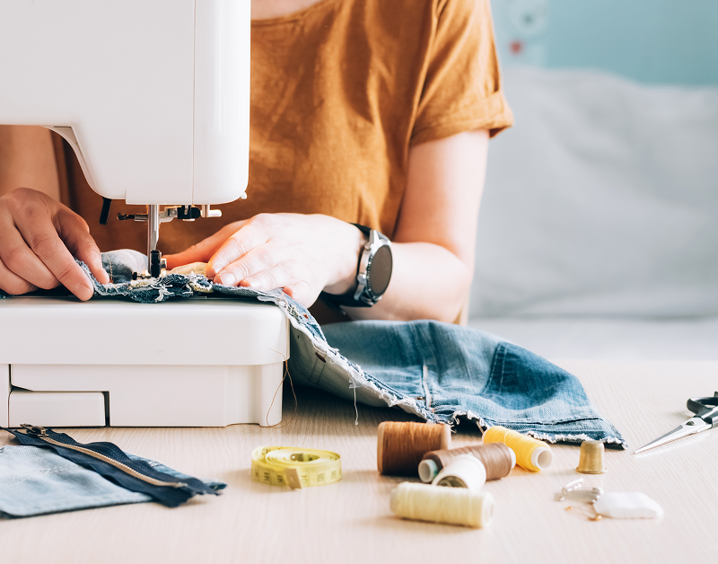 Person sewing denim fabric on machine