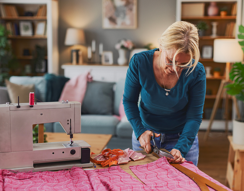 Woman cutting fabric beside sewing machine