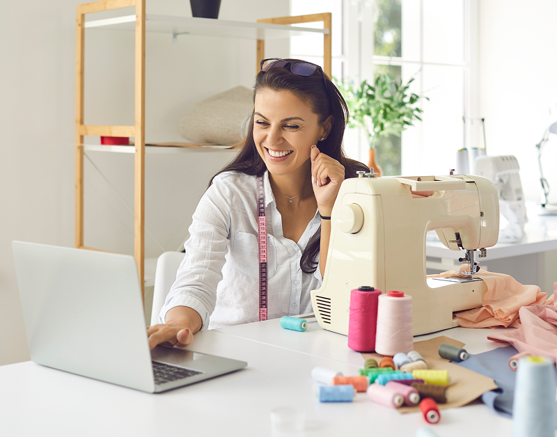 Seamstress working with sewing machine and laptop
