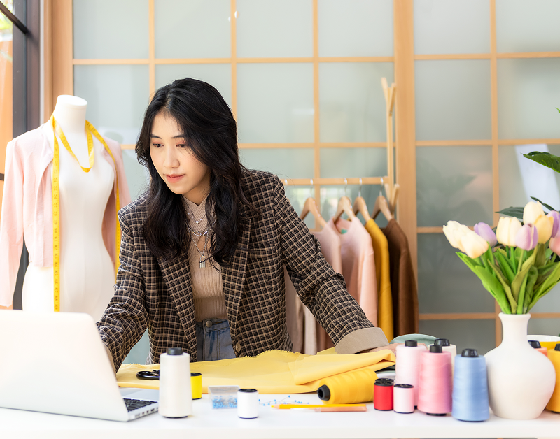 Designer using laptop with fabrics