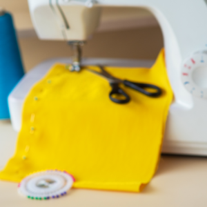 A sewing machine with yellow fabric and scissors.
