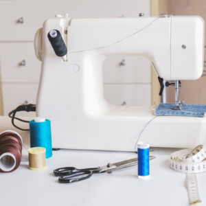 A sewing machine with spools of thread, scissors, and measuring tape.