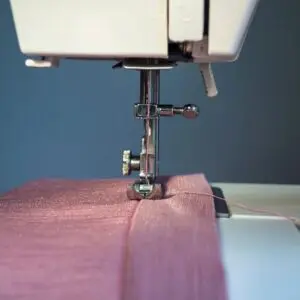Close-up of a sewing machine stitching purple fabric.