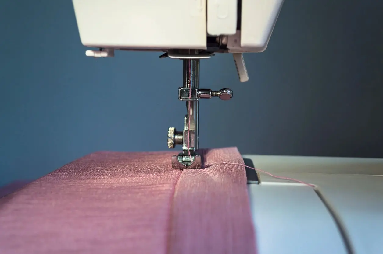 Close-up of a sewing machine stitching purple fabric.