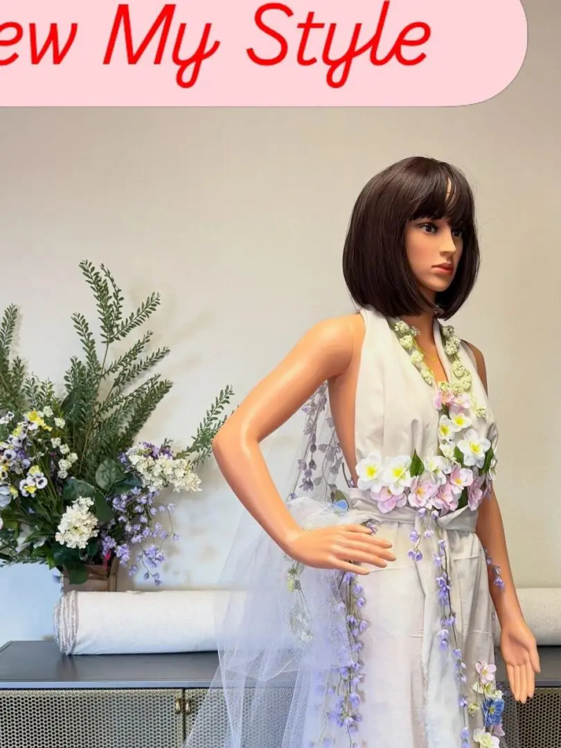 Mannequin dressed in a stylish outfit beside a floral arrangement.